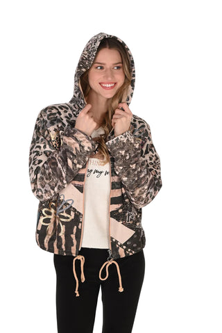A woman modeling a leopard print zip-up hoodie with beige graphic accents, worn over a cream graphic t-shirt and black pants, against a plain white background.