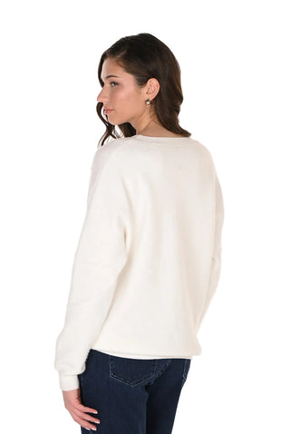 Woman wearing a white sweater and dark jeans on a white background