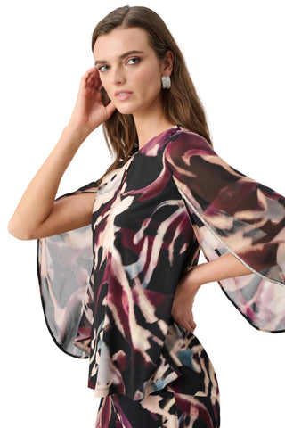 Woman wearing a patterned dress with sheer sleeves against a white background