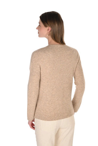 Woman wearing a beige sweater and white pants on a white background