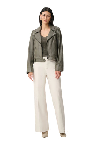Woman wearing a green jacket and white pants on a white background
