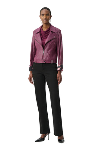 Woman wearing a purple leather jacket and black pants on a white background