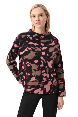 Woman wearing a pink and brown camouflage sweater on a white background