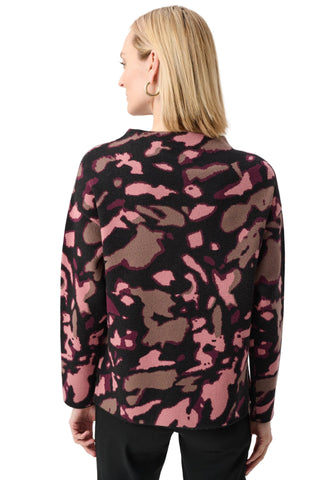 Person wearing a pink and black camouflage-patterned cardigan on a white background