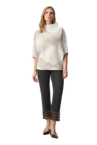 Woman wearing a patterned top and black pants on a white background