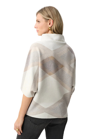 Woman wearing a patterned poncho against a white background