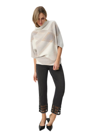 Woman wearing a patterned poncho and black pants with cut-out details on a white background