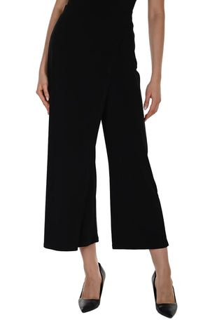 Person wearing a black dress with wide-leg pants on a white background