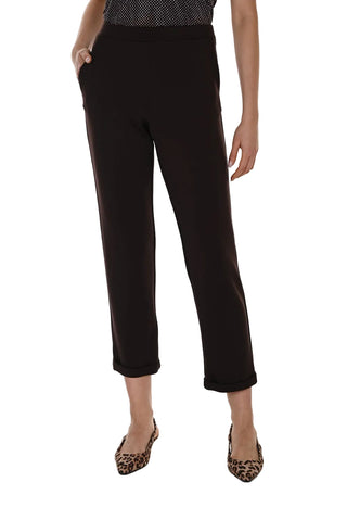 A model wearing black cropped trousers with a subtle side stripe detail, paired with leopard print pointed-toe flats, shown against a plain white studio background.