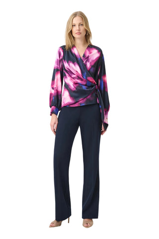 Woman wearing a colorful top and navy pants on a white background