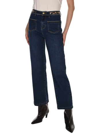 A model wearing dark blue straight-leg denim jeans with a decorative gold-tone belt, paired with black pointed-toe heeled boots against a white studio background.