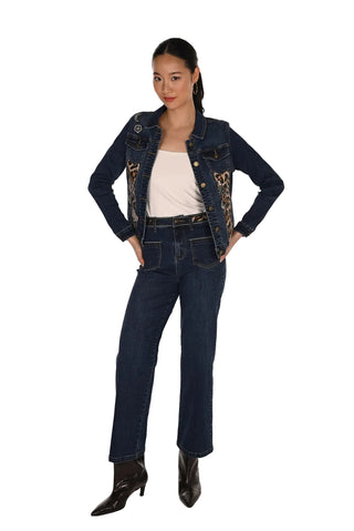 A model wearing a dark wash denim jacket with gold embroidery, matching dark blue jeans, a white tank top, and black pointed-toe heeled boots, standing against a white studio background.