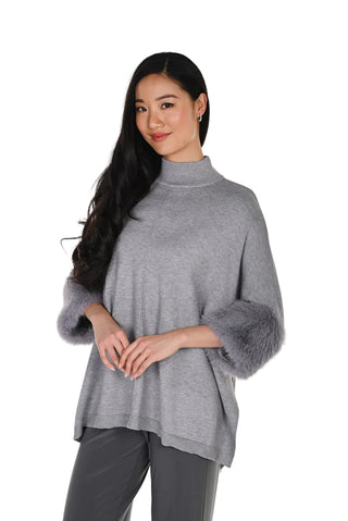 Woman wearing a gray sweater with fur cuffs on a white background
