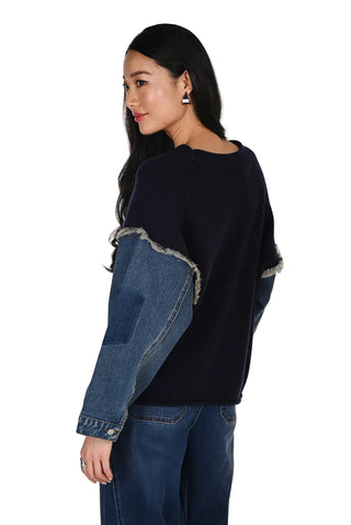 Woman wearing a black sweater with denim patchwork design on a white background