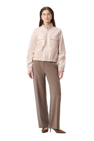 Woman wearing a light pink jacket and beige pants on a white background