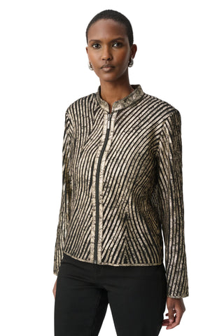 A woman modeling a long-sleeve zip-front jacket with a textured, metallic-looking vertical stripe pattern in beige, gold, and black, paired with black pants against a light gray studio background.