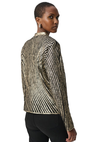 A model shown from the back wearing a long-sleeve cropped jacket with a metallic gold and black vertical stripe pattern, paired with black pants, against a plain light gray background.