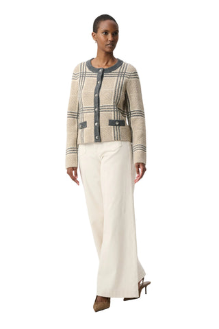 A model is shown from the head to toe wearing a beige and gray plaid cardigan with dark gray trim, paired with off-white wide-leg trousers and brown pointed-toe heels, against a plain light gray studio background.