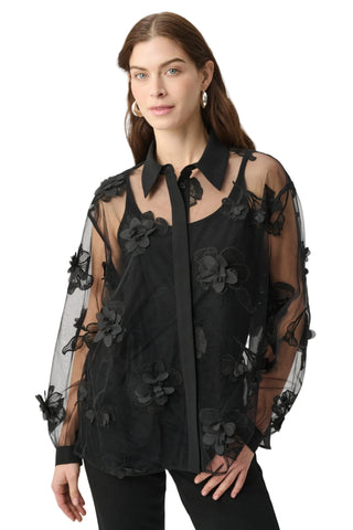 A woman modeling a black sheer mesh blouse with 3D floral appliqués and a black collar, paired with black pants against a clean white studio background.