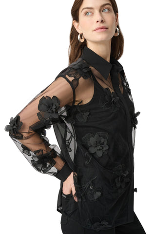 Woman wearing a black floral embroidered blouse against a white background