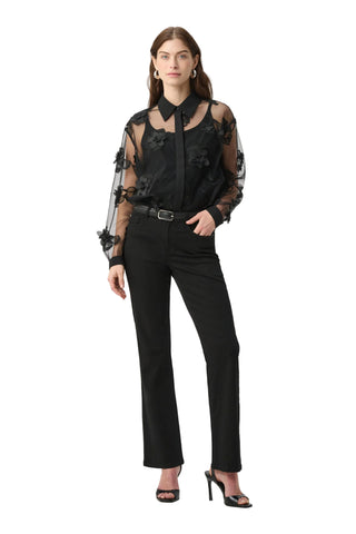 Woman wearing a black outfit with sheer sleeves on a white background