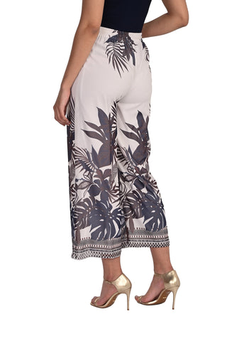 Tropical leaf patterned pants worn by a person on a white background