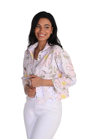 Woman wearing a light-colored floral blouse with white pants on a plain background