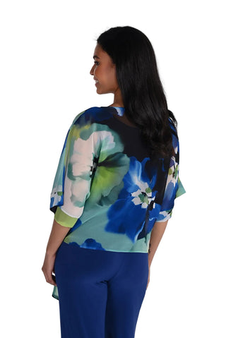 Woman wearing a colorful floral top and blue pants on a white background