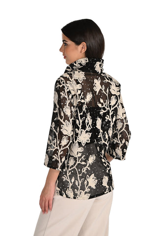 Woman wearing a black floral patterned blouse against a white background