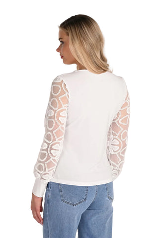Woman wearing a white long-sleeve top with lace sleeves against a light background