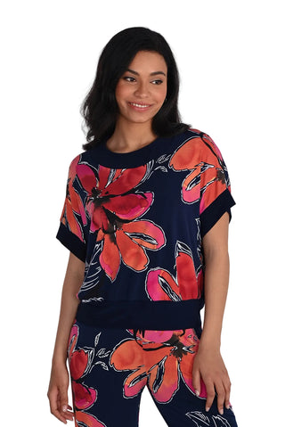 Woman wearing a navy blue top with large red floral patterns on a white background