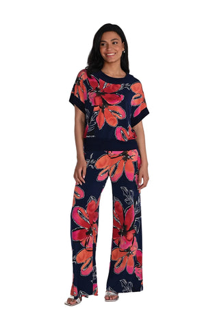 Woman wearing a navy outfit with large pink floral patterns on a white background