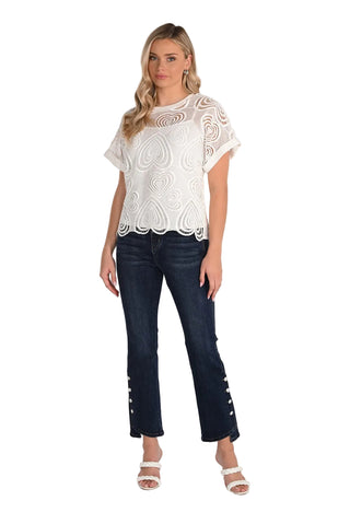 Woman wearing a white lace top and dark blue jeans on a white background
