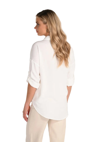 Woman wearing a white blouse with rolled-up sleeves on a plain background