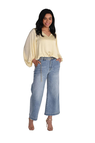 Woman wearing a light yellow blouse and blue jeans on a white background