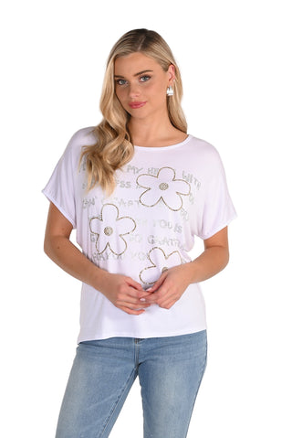 Woman wearing a white t-shirt with floral designs on a plain background