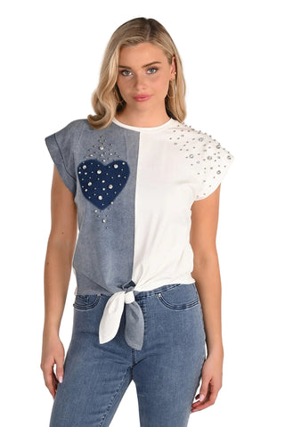 Woman wearing a two-tone top with a heart design and blue jeans on a white background