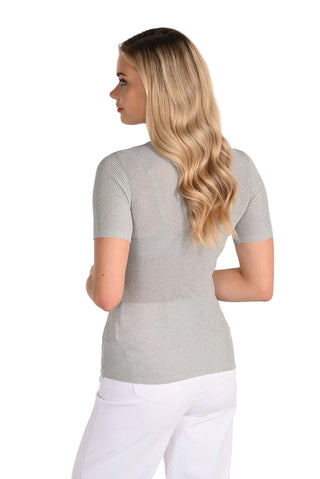 Woman wearing a gray short-sleeve top and white pants on a plain background