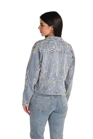 Woman wearing a light blue denim jacket with floral embroidery on a white background