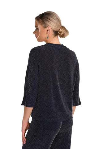 Woman wearing a dark gray sweater and pants on a plain background