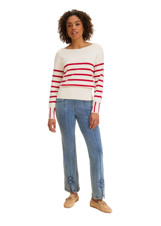 Woman wearing a white sweater with red stripes and blue jeans on a beige background