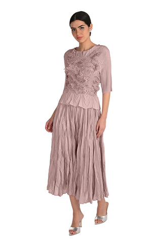 Woman wearing a pink dress with floral embroidery on a white background