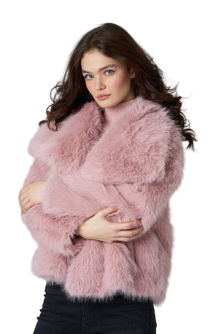 Woman wearing a pink fur coat against a plain background