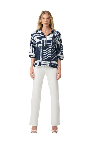 A woman modeling a navy and white abstract patterned button-up shirt with three-quarter sleeves, paired with white wide-leg pants and clear high-heeled sandals, against a plain light gray studio background.
