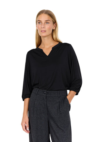 Woman wearing a black top and dark gray pants against a white background