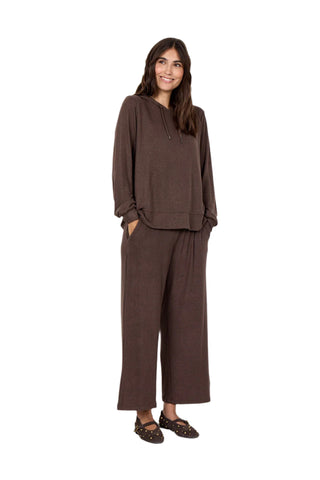 Woman wearing a brown outfit standing against a white background