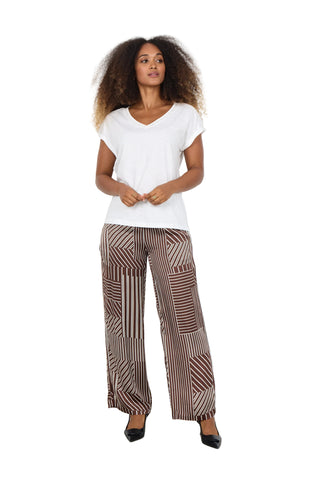 Woman wearing a white top and patterned pants against a white background