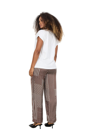 Woman wearing a white top and patterned pants against a white background