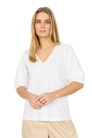 Woman wearing a white blouse against a plain background
