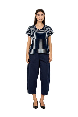 Woman wearing a striped shirt and navy pants against a white background